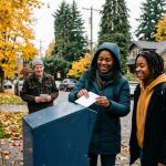 Vote by mail 2026, mother and daughter returning a ballot at a drop box in the Pacific Northwest